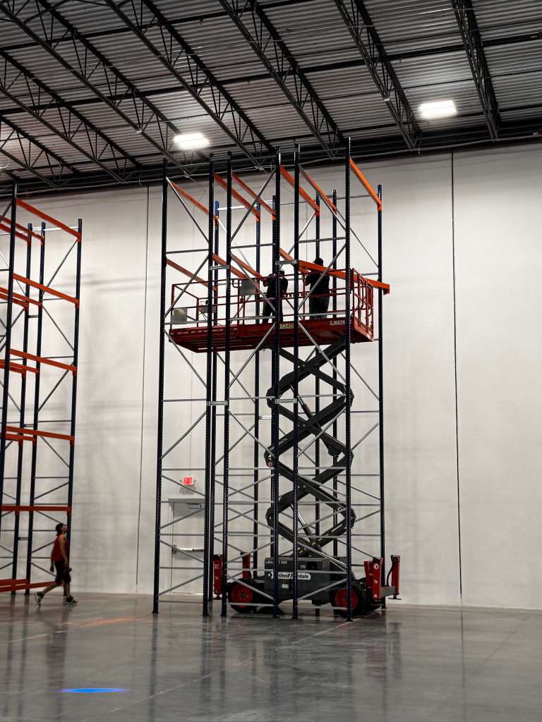 Orozco's Racks crew member on scissor lift installing high-bay racks